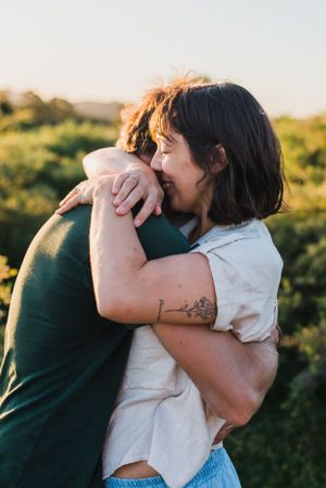 Mamá y Papá abrazándose y sonriendo en un sesión familiar durante el atardecer en Tandil