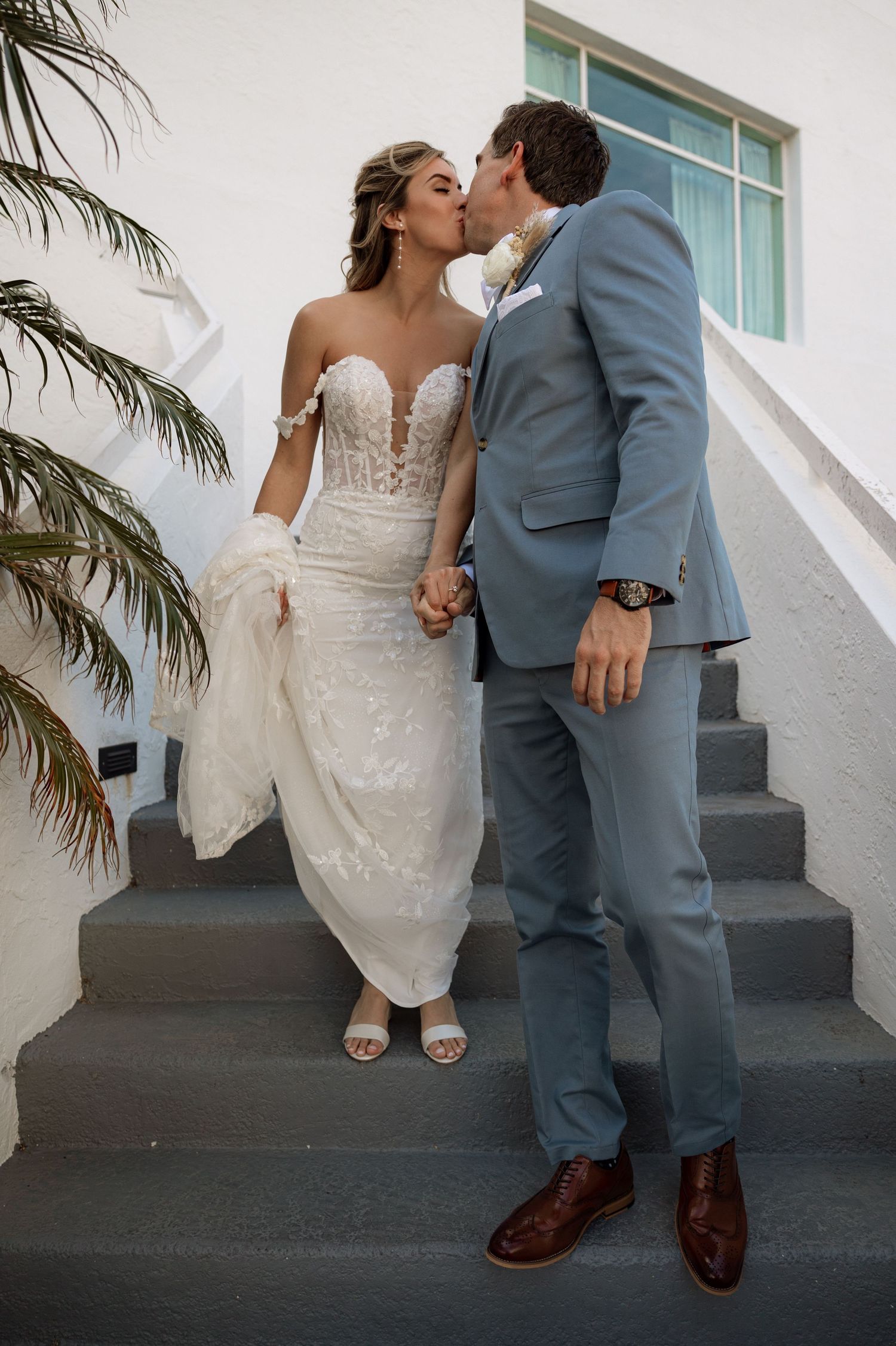 Wedding couple sharing romantic kiss on modern staircase.