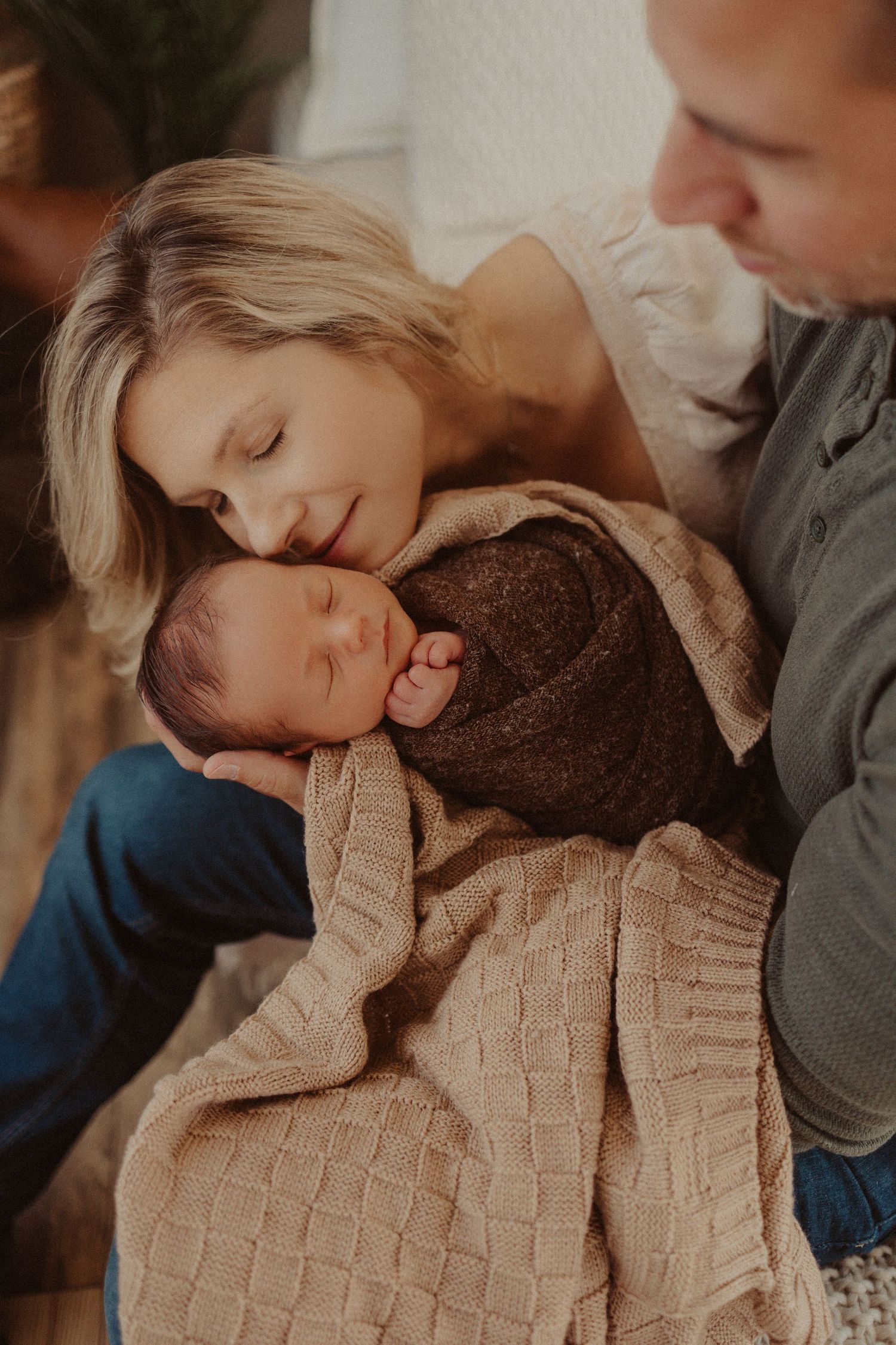 mom and dad snuggle in close- newborn photography