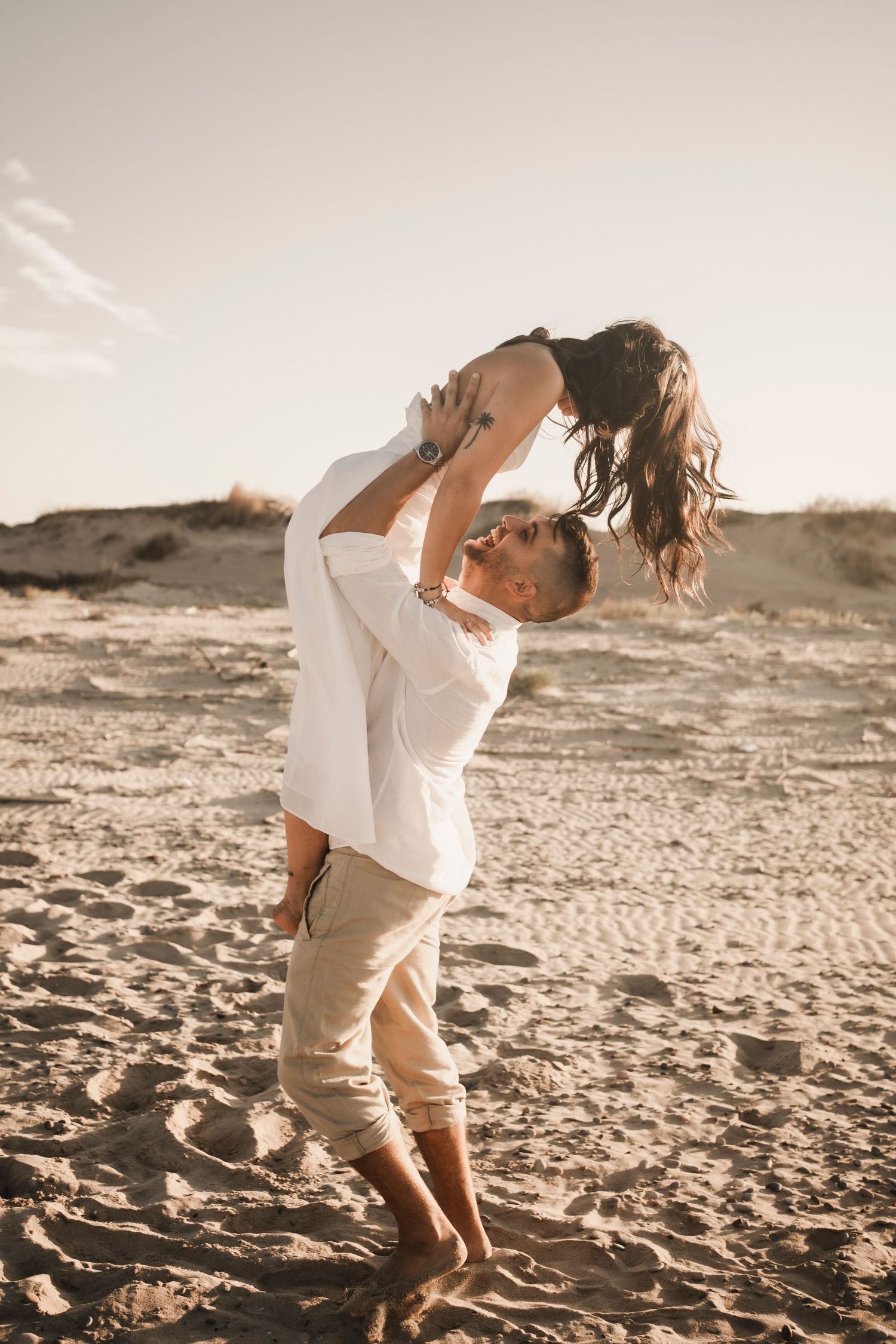 Couple having fun on their engagement photoshoot at the beach in Venice.