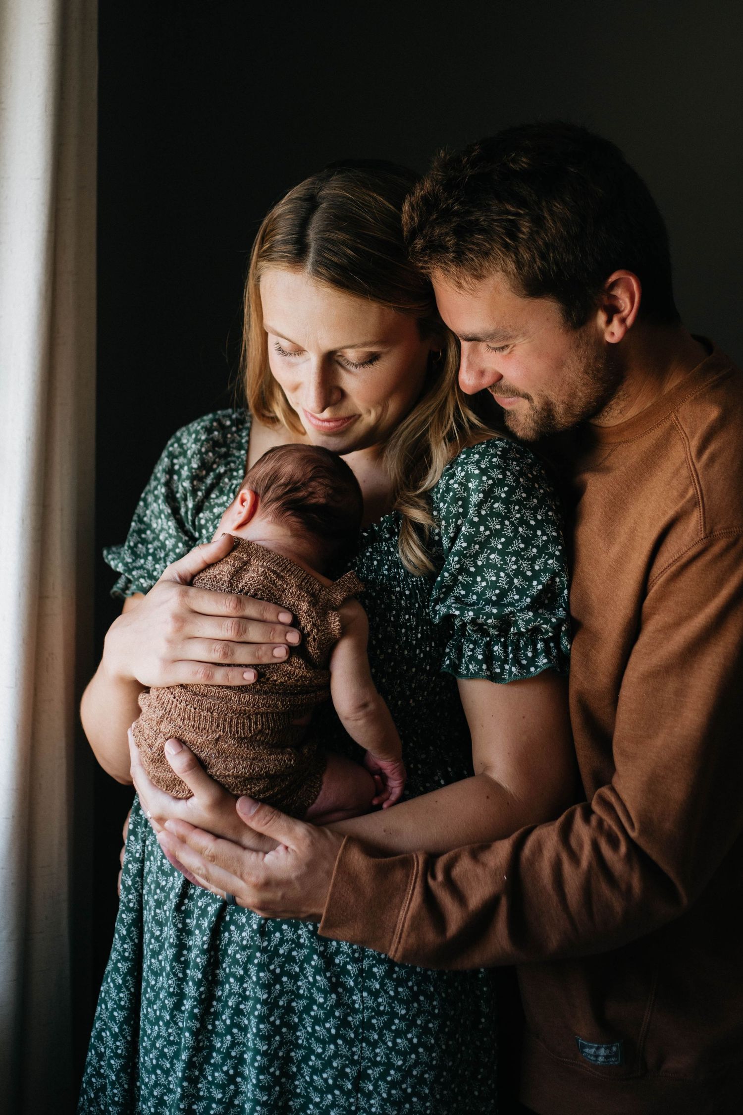 Mother and father holding newborn baby in their newborn session with Devin Justine Photography.
