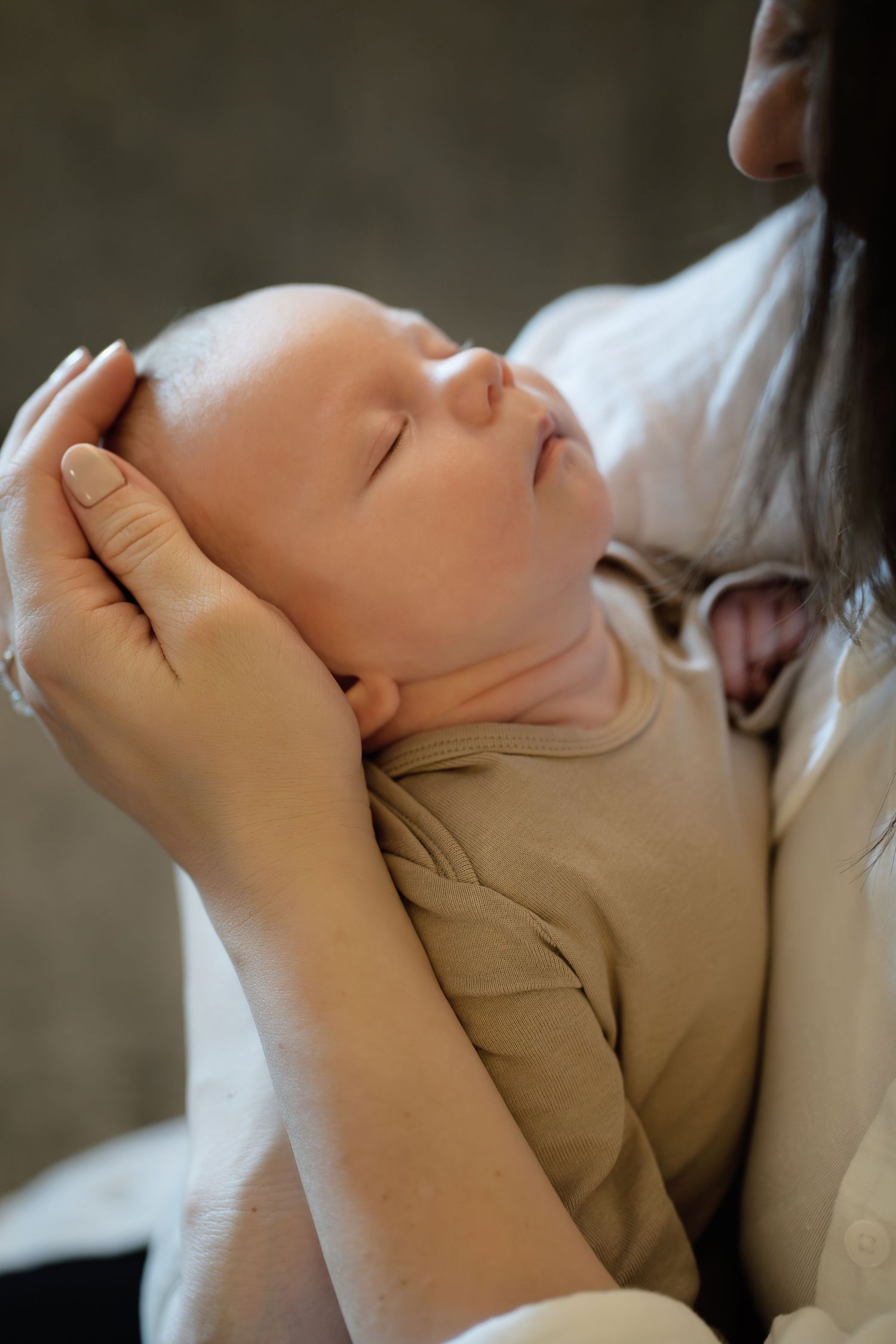A serene close-up of a sleeping baby being cradled in soft natural light.