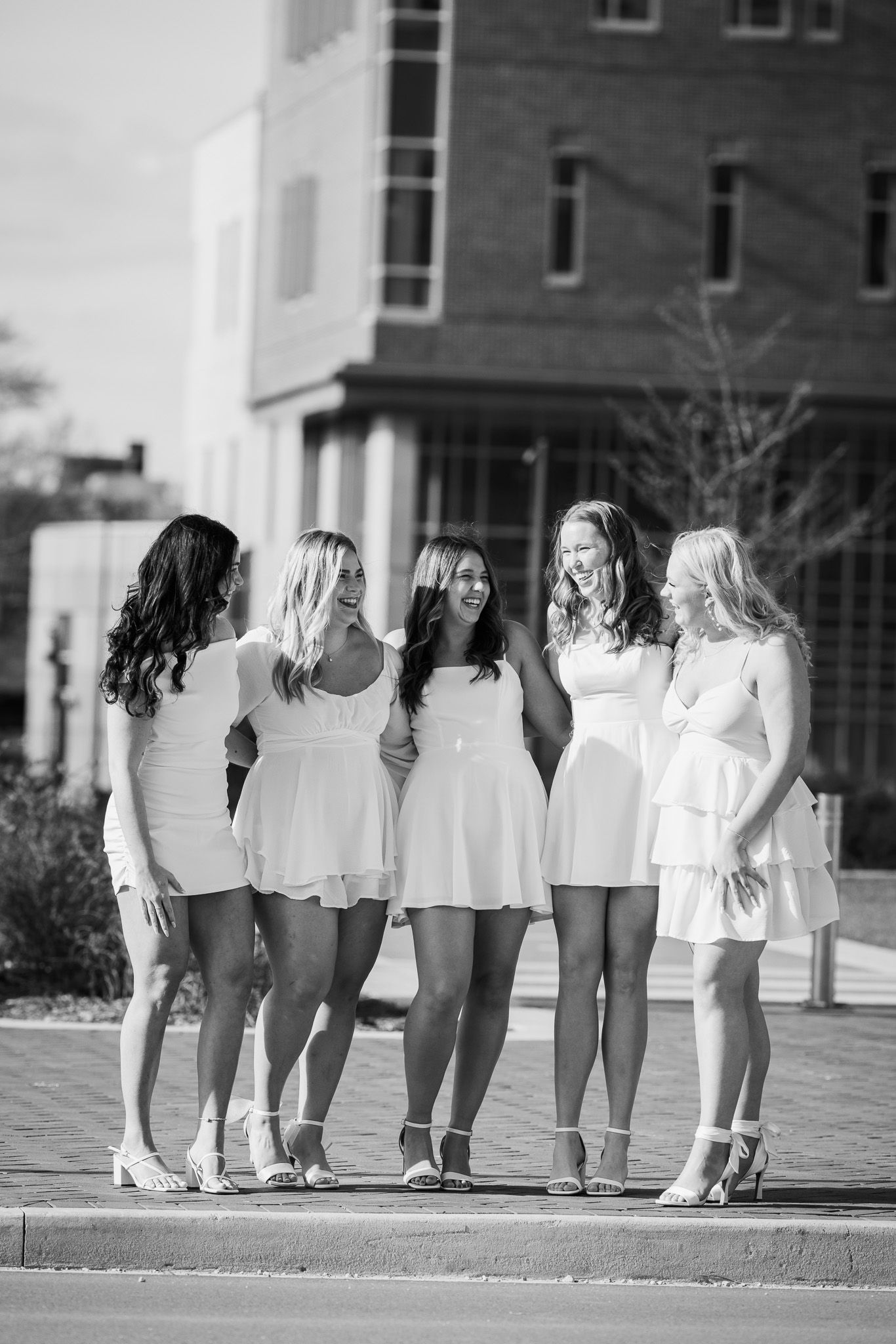 Black and white photo of students lined up in matching white outfits on campus.