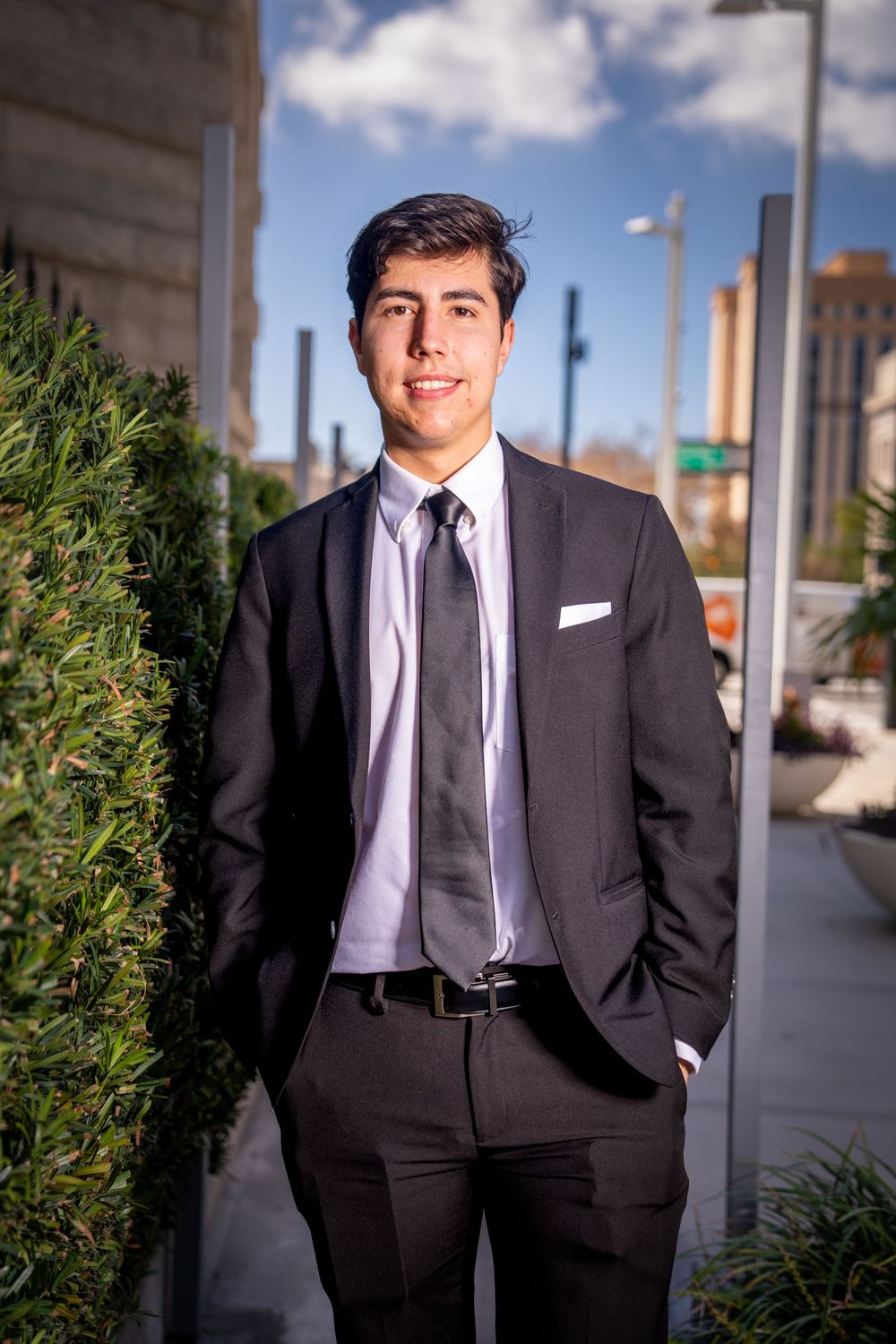 Young professional man in black suit and tie smiling outdoors in urban setting on sunny day in Tampa.