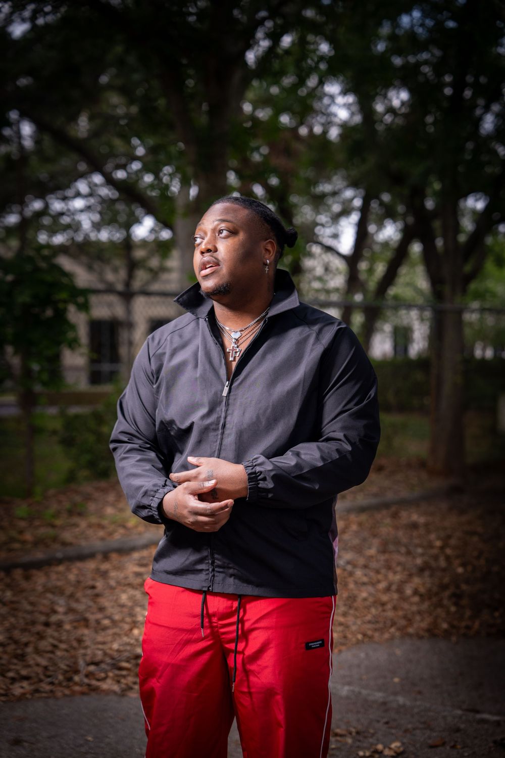 Young man in black jacket and red pants posing outdoors in park setting for portrait photo in Tampa.