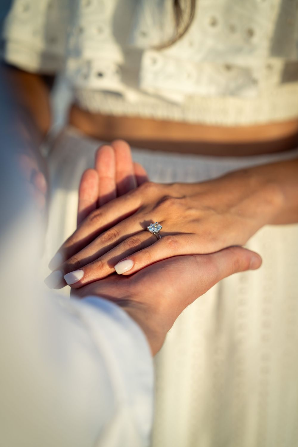 Close-up of engaged couple holding hands showing diamond engagement ring on womans finger in Tampa.