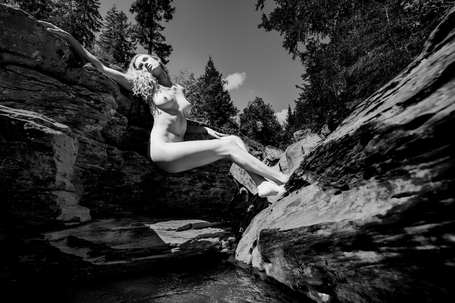 Black and white photograph of a swimmer diving into rocky waters.
