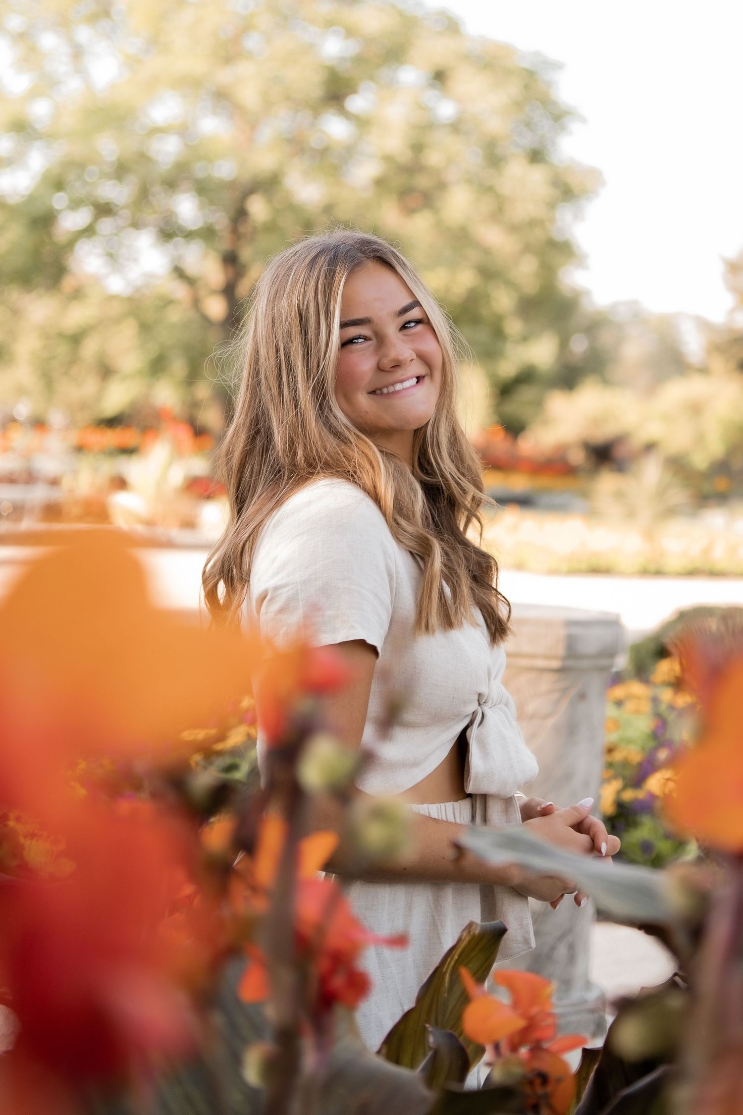 A white summer outfit contrasts beautifully with orange and red flowers in the foreground.