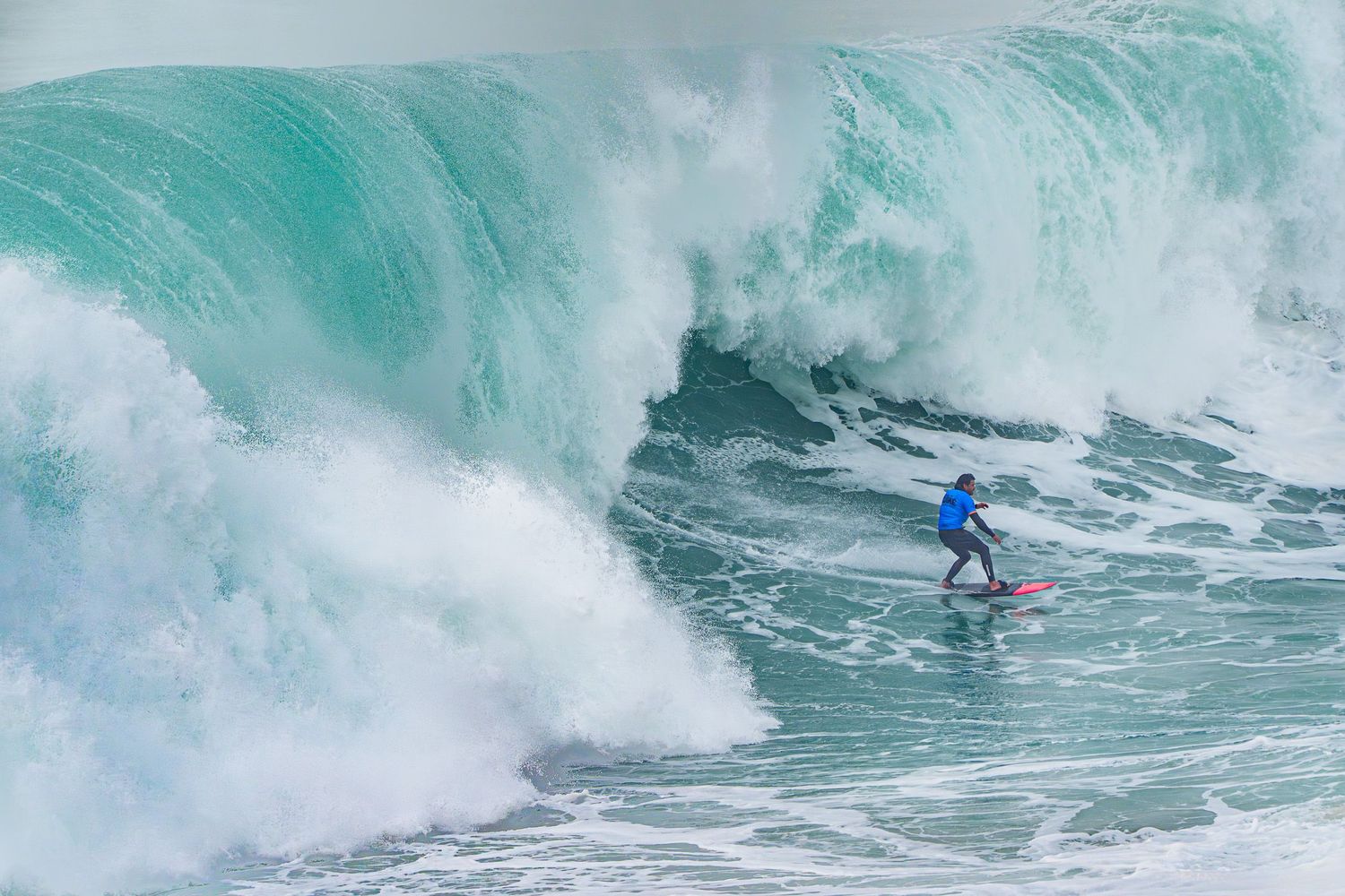 Dramatic storm front over ocean creates misty white spray against dark blue water.
