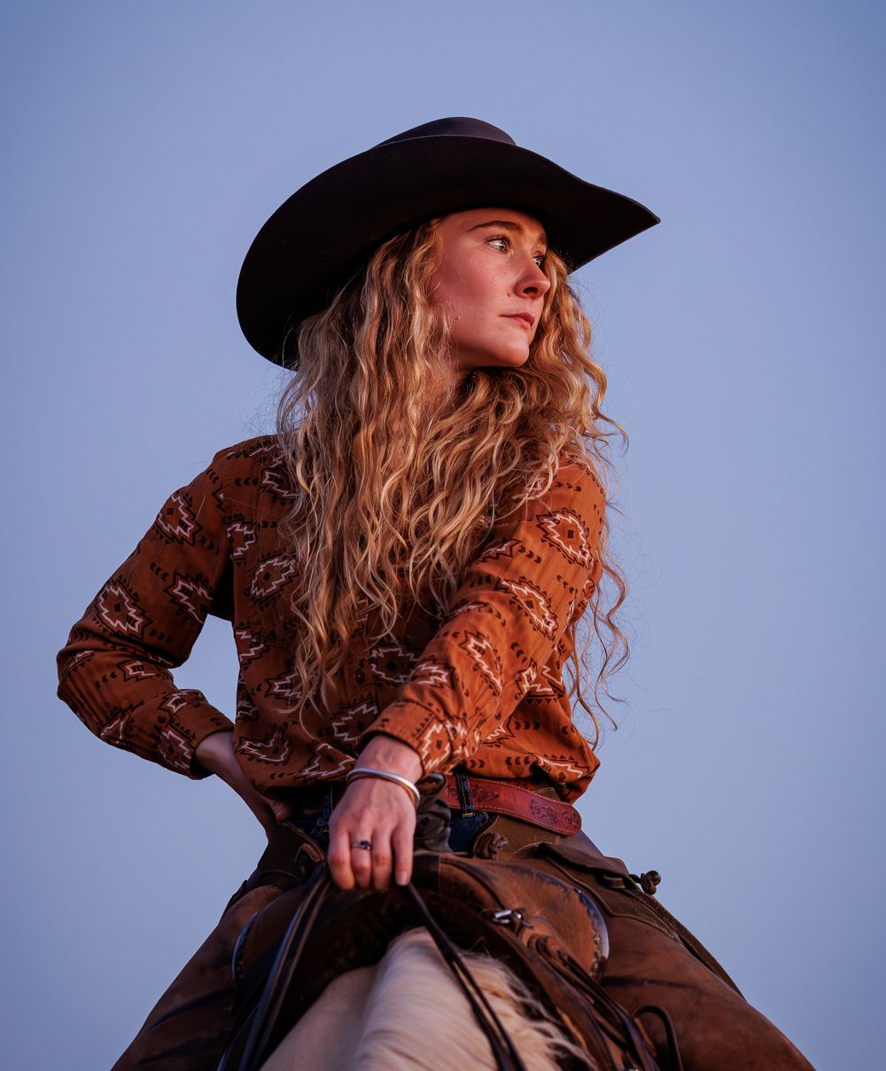 A person in a black hat and brown leather jacket poses against a blue backdrop in a series of dramatic angles.
