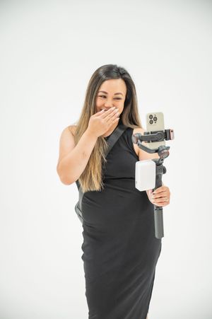 A series of three photos shows a photographer in a black top crying and covering their face with one hand while holding a camera.