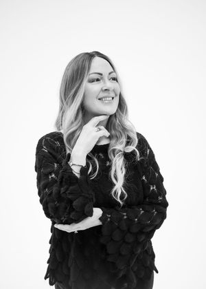 A person in a black textured sweater laughs and poses in a sequence of four studio shots against a white background.