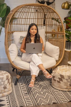 Stylish home office setup featuring rattan egg chair, geometric rug, and laptop workspace.