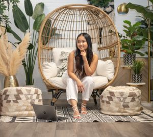 Cozy boho-style indoor setting with hanging chair, plants, and modern workspace accessories.