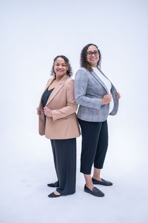 Two people in business attire pose together against a white backdrop in a series of playful studio shots.