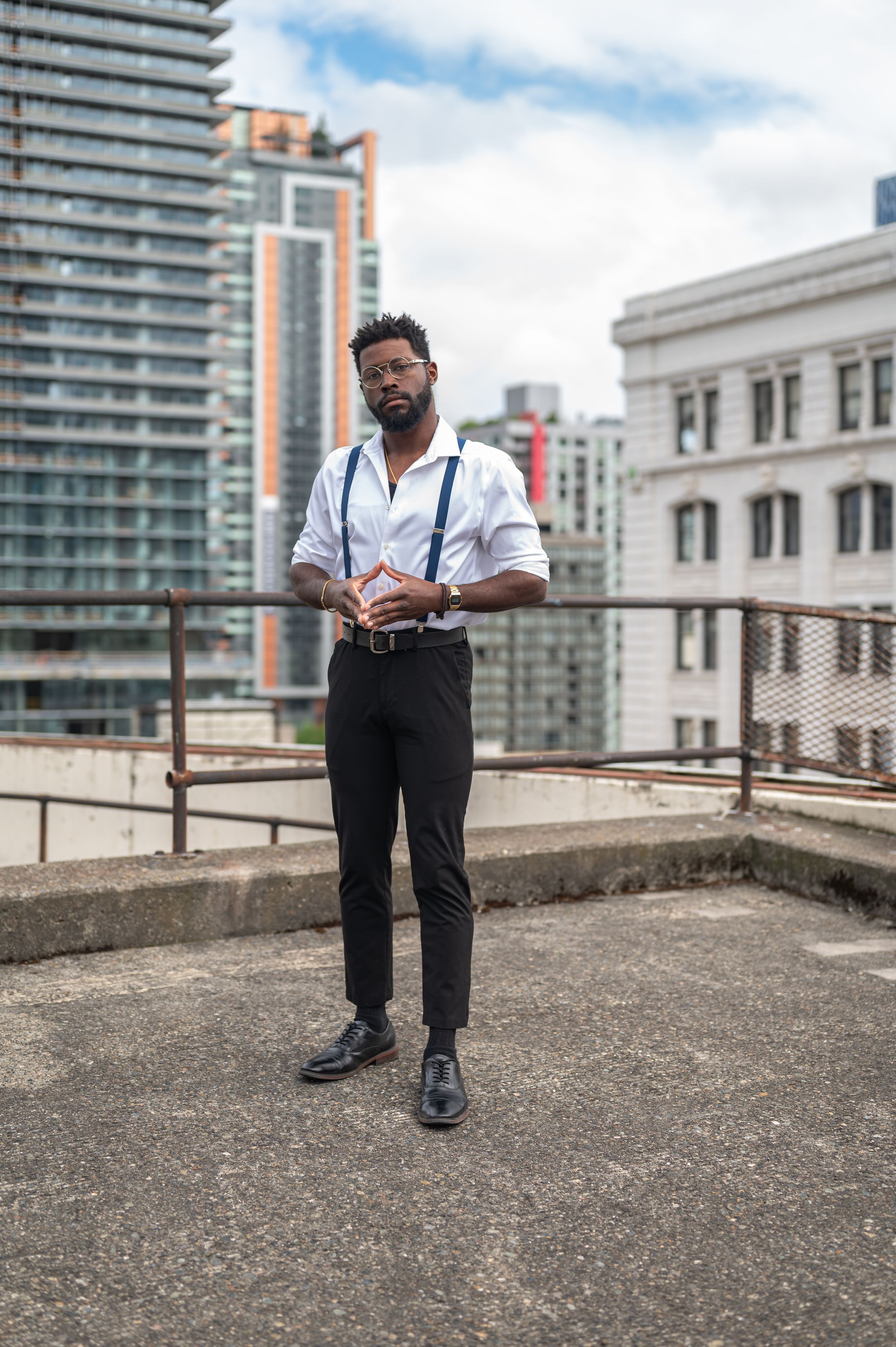 Elegant formal attire with white shirt and suspenders against city backdrop.