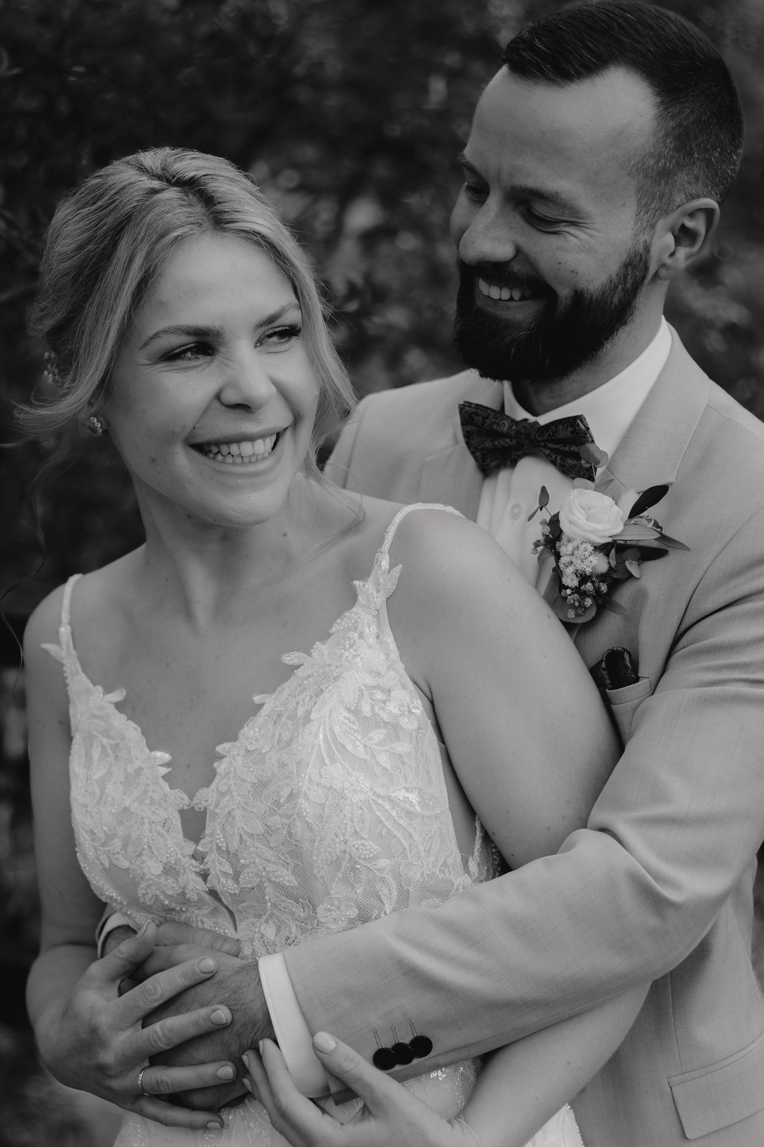 Joyful wedding portrait in black and white with natural outdoor backdrop.