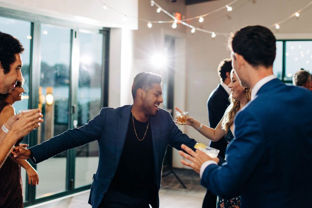 Wedding guest dancing energetically among friends at reception party.