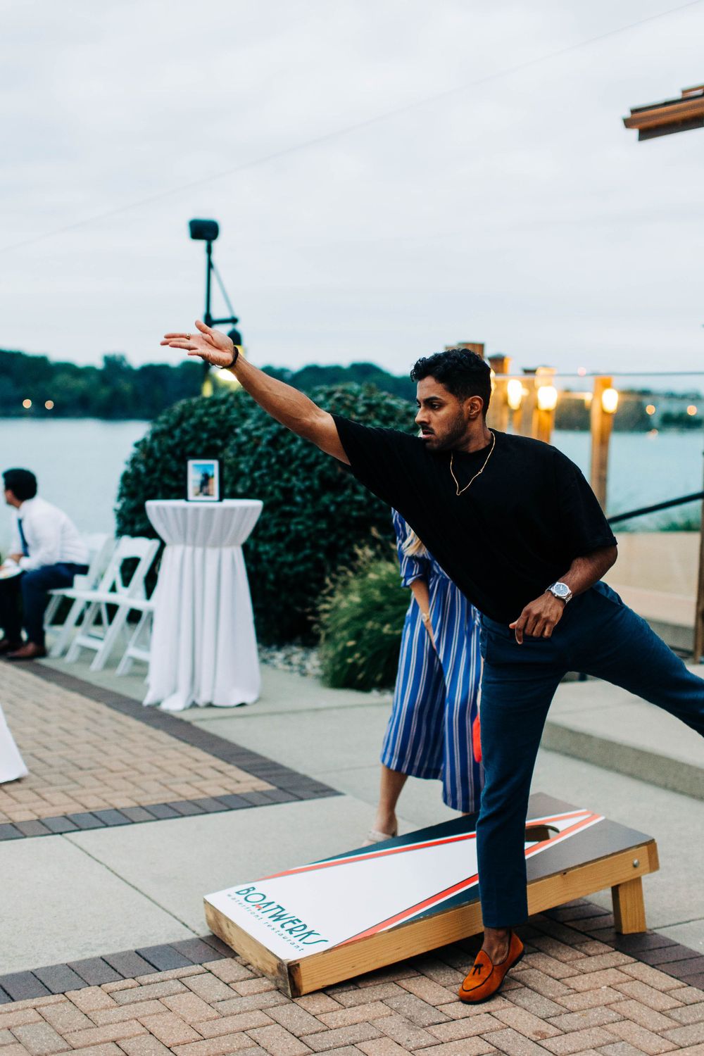 Guest plays cornhole game on outdoor patio during wedding reception.