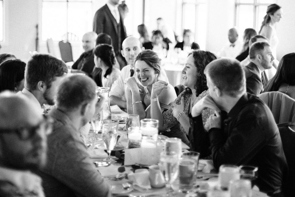 Wedding reception guests enjoy dinner and conversation at tables with candlelight.