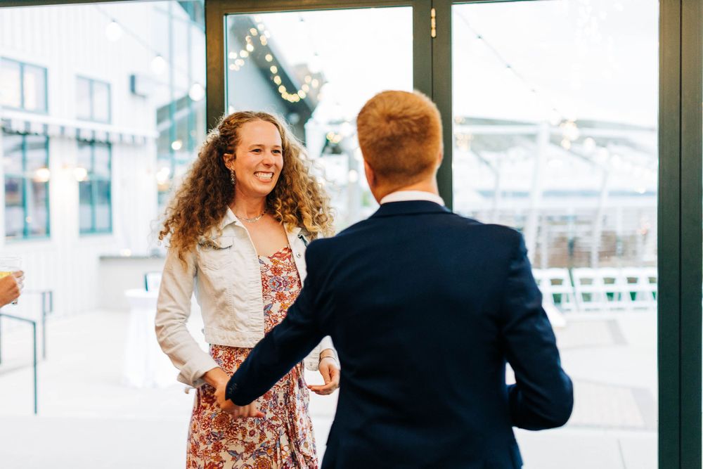 Two people having an animated conversation in front of glass doors.