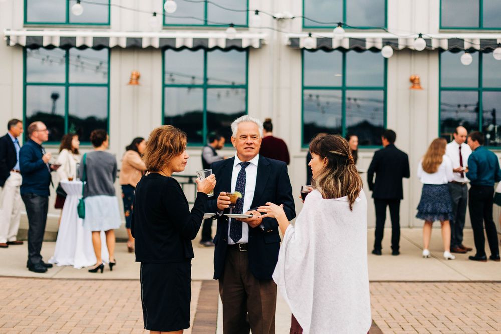 Wedding guests mingle and socialize outside a modern building during reception.