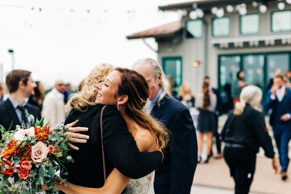 Emotional embraces shared during wedding reception outside venue with floral bouquet.