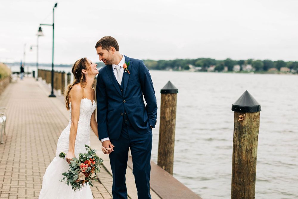 Newlyweds share an intimate moment along a waterfront boardwalk.