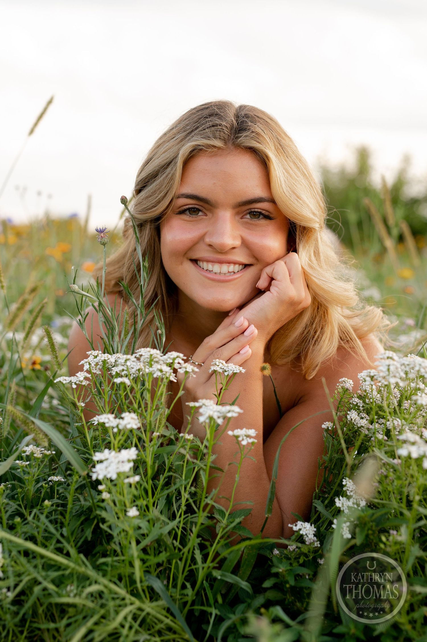 A dreamy outdoor portrait amid white wildflowers and natural greenery on a sunny day.