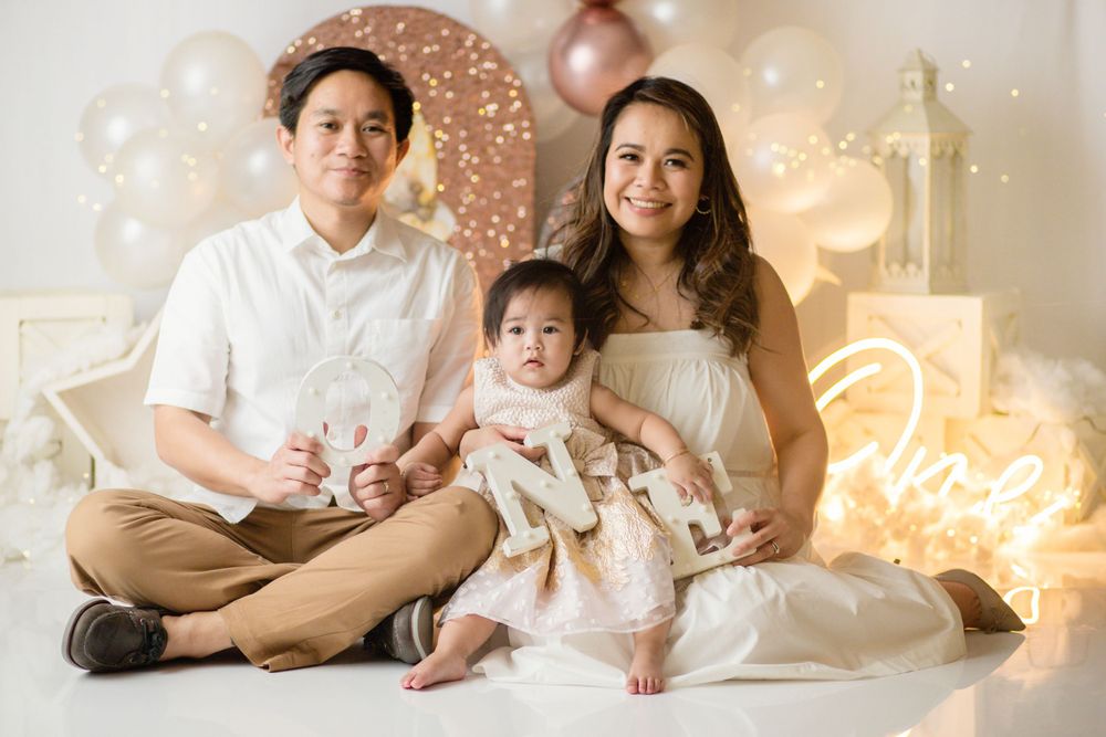 Studio portrait with rose gold balloon arch and neon light decorations.