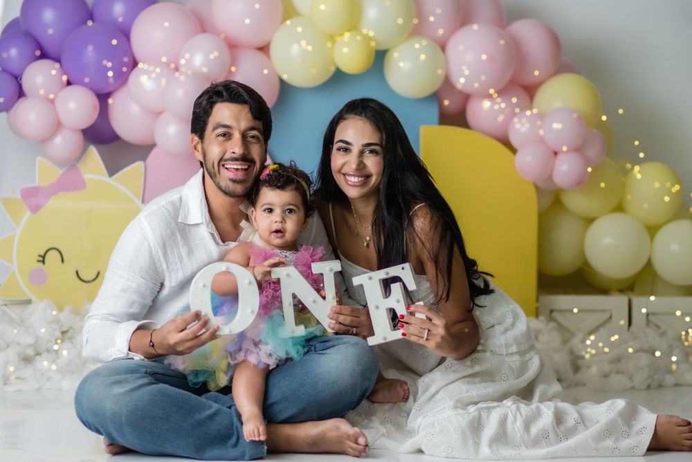 First birthday photo setup with pastel balloon arch and letter decorations.