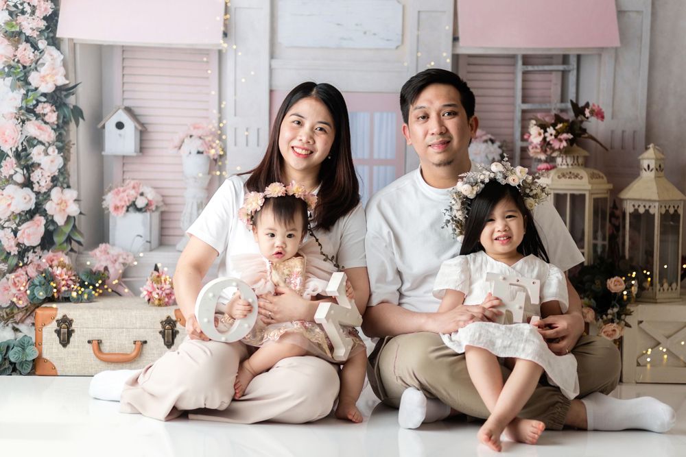 Studio portrait with floral decor and family in coordinated white and beige outfits.