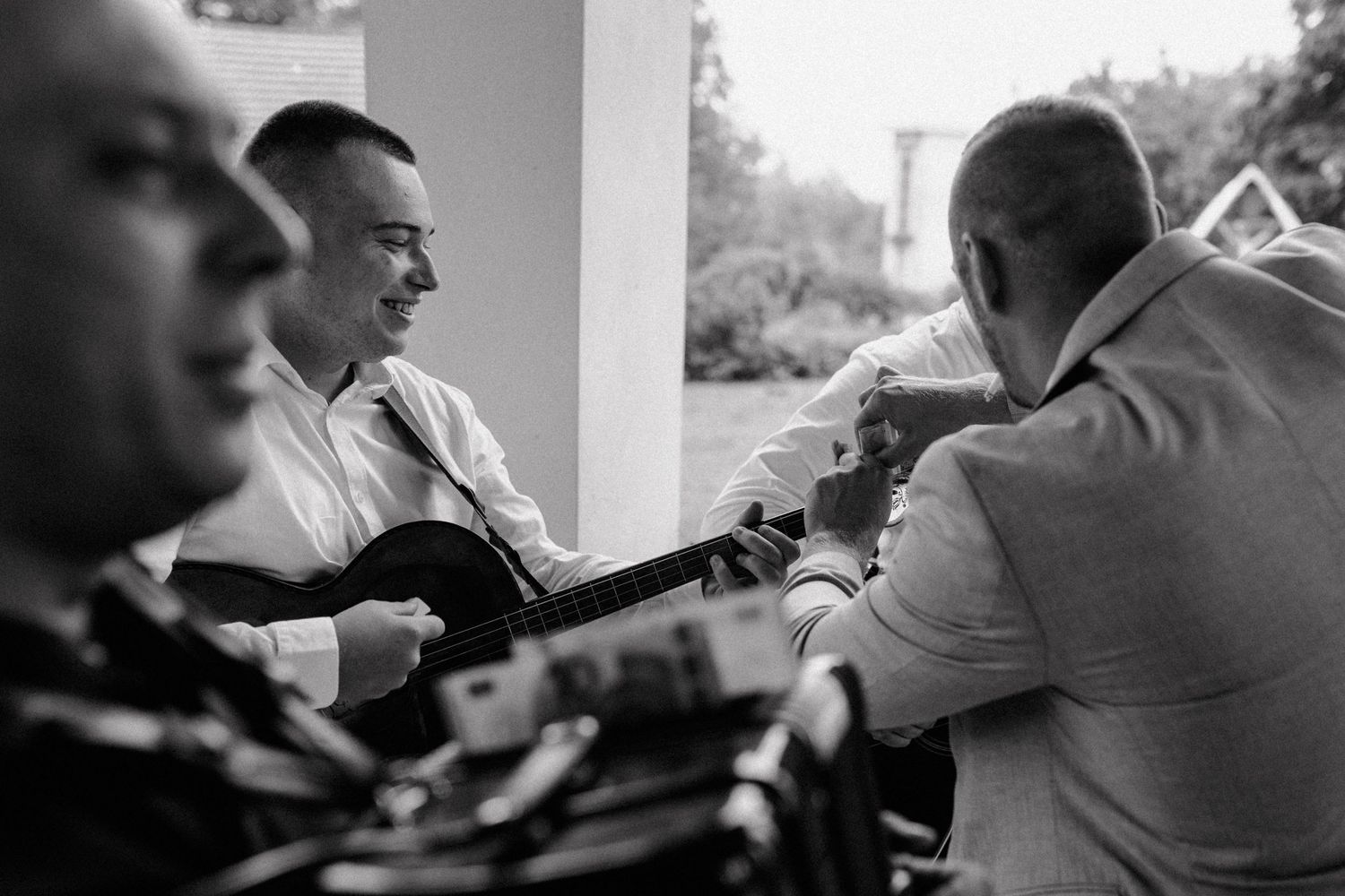 Musicians playing instruments on a porch in black and white photography.