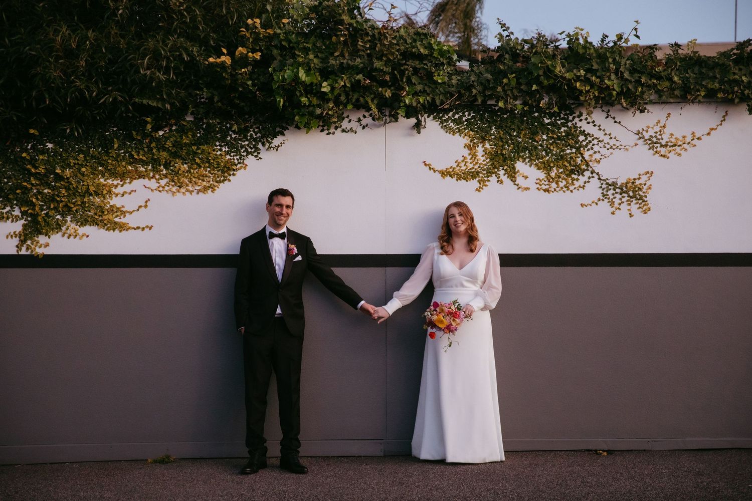 couple holding hands infront of wall with ivy in a Melbourne street, Post Office Hotel, Coburg