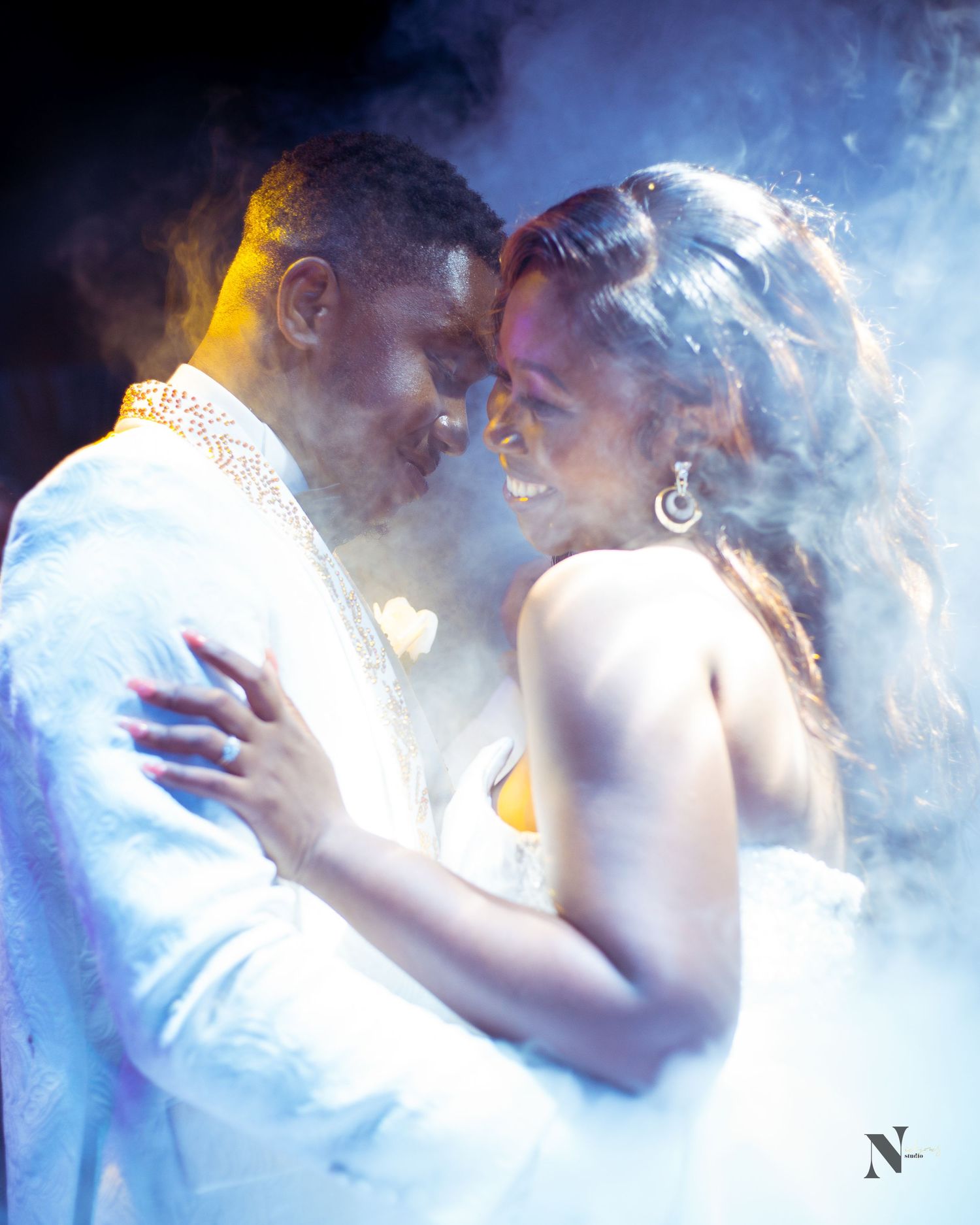 An atmospheric photo of a couple in white surrounded by misty lighting effects.