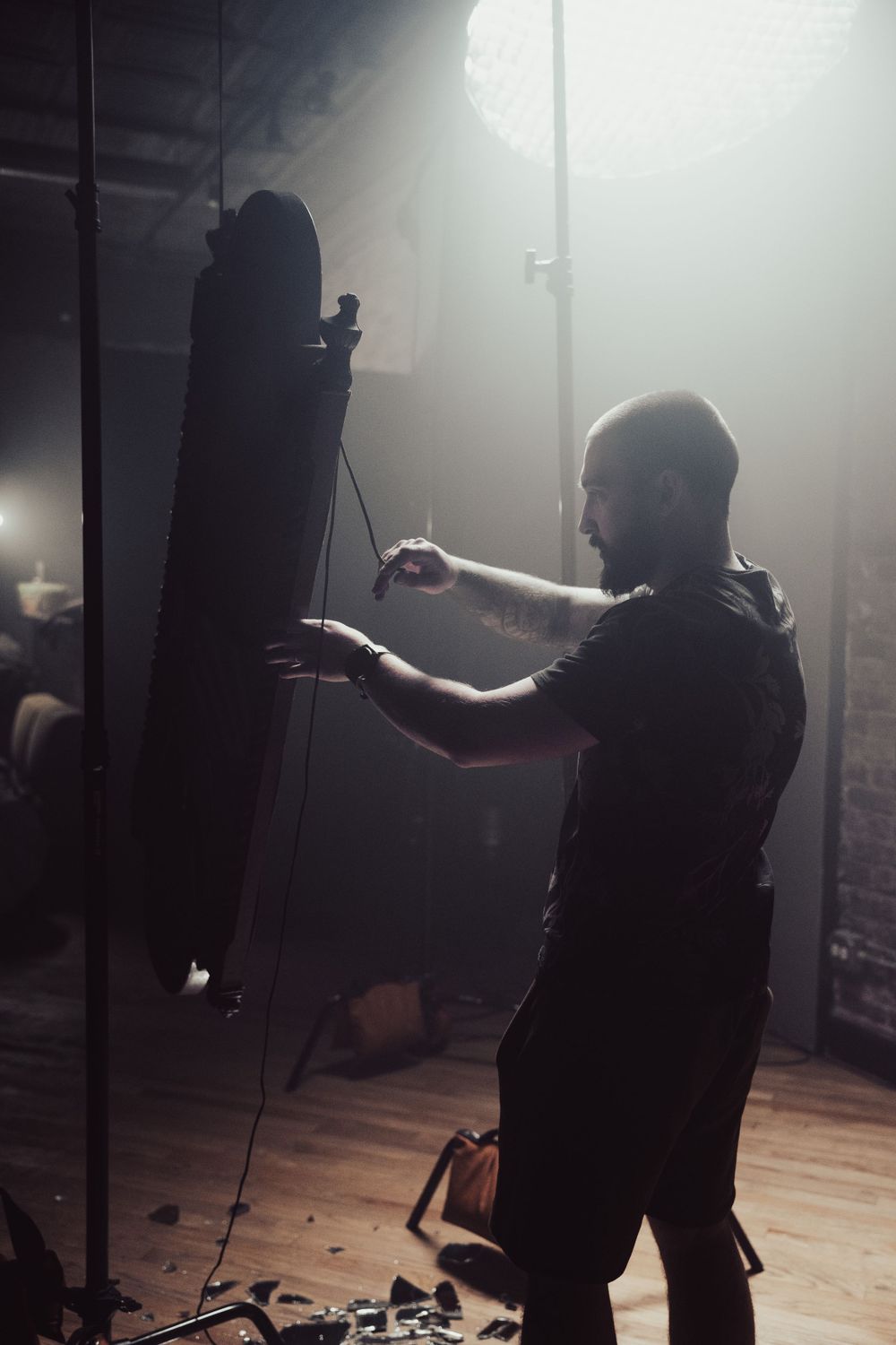 Production crew member working with light modifiers in atmospheric studio setting.