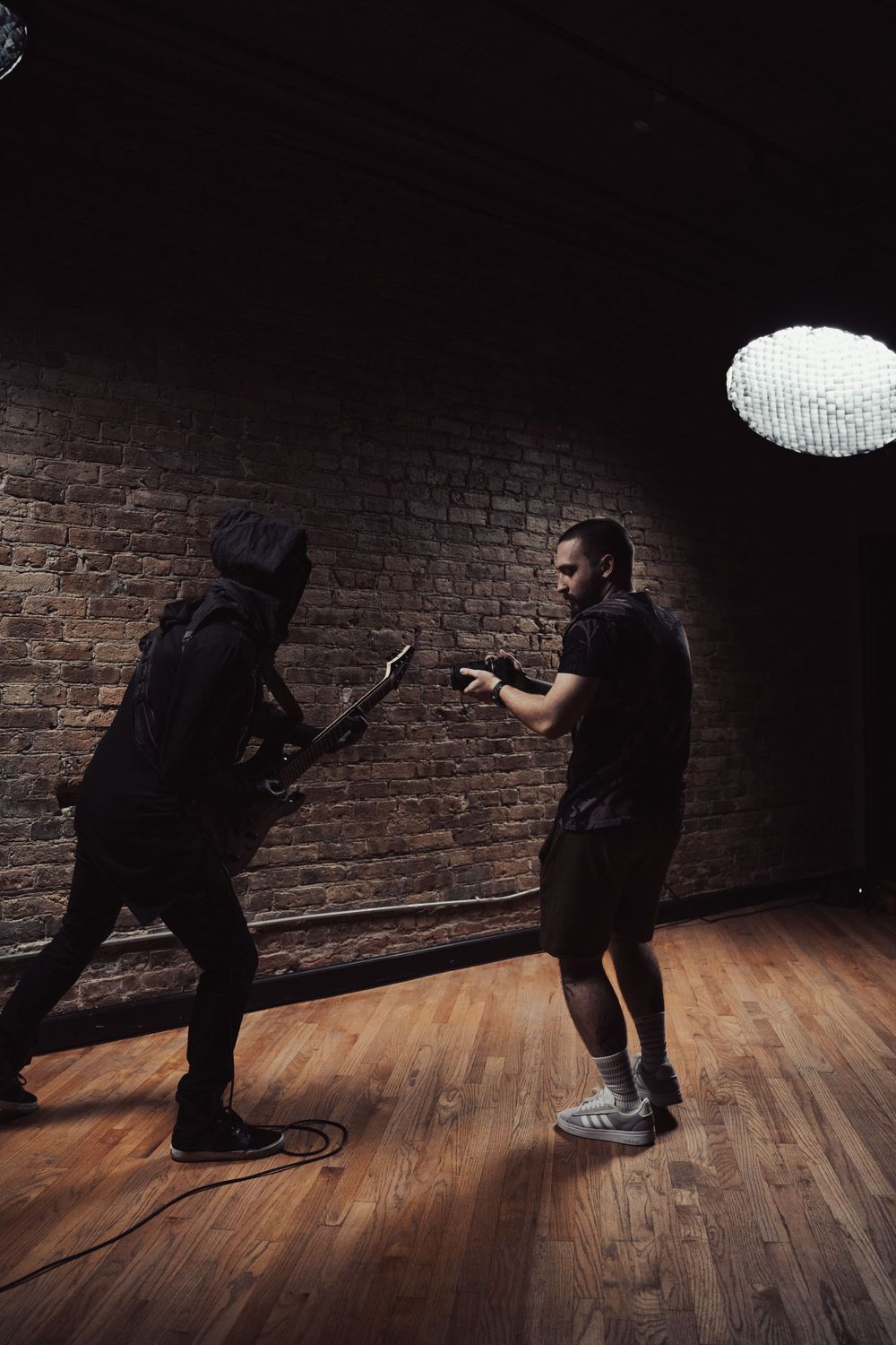 Dynamic studio photography session with dramatic lighting and exposed brick backdrop.