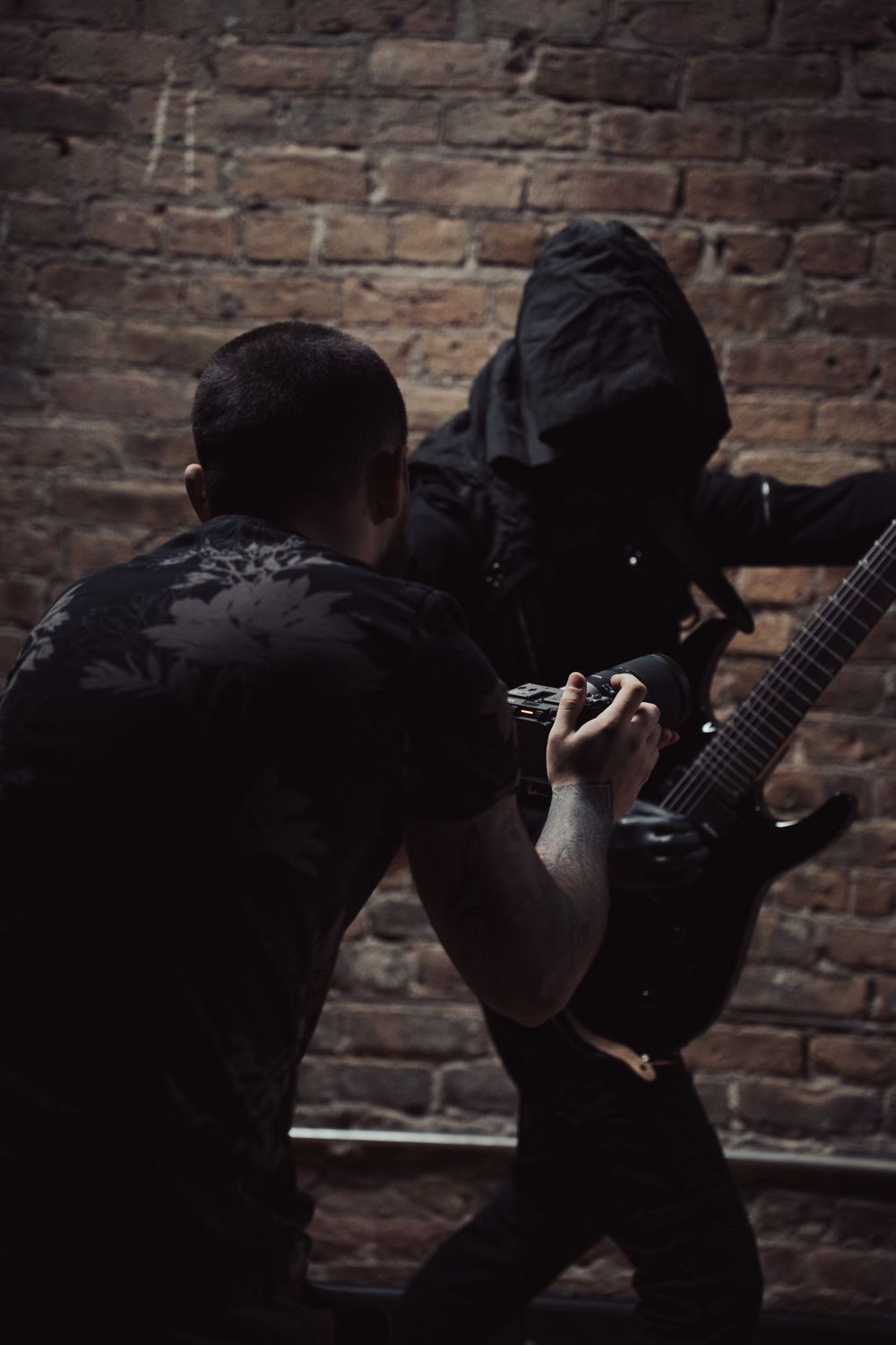 Photographer capturing dramatic action poses in dark studio setting.