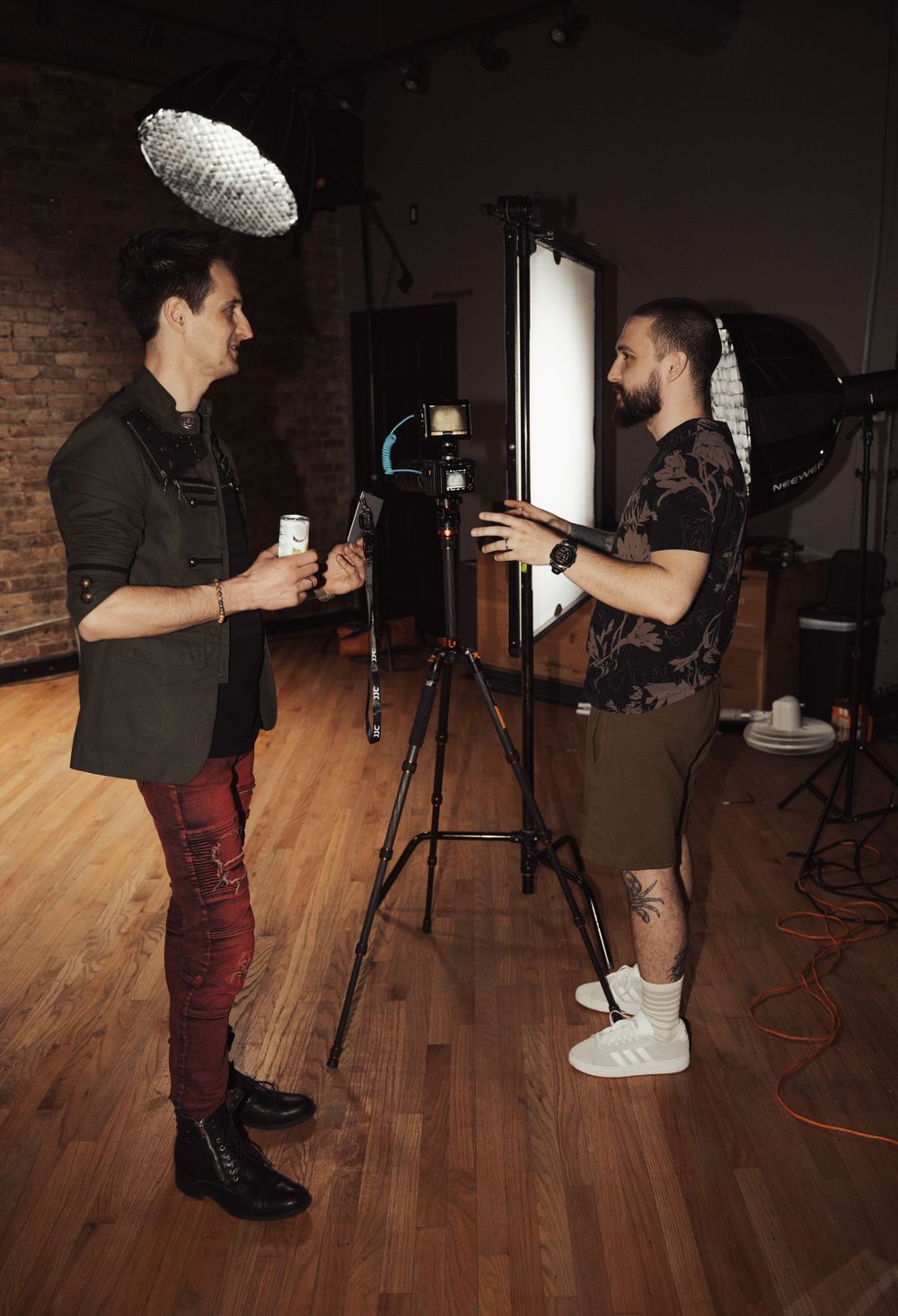 Two musicians discussing setup details under studio lighting on wooden floor.