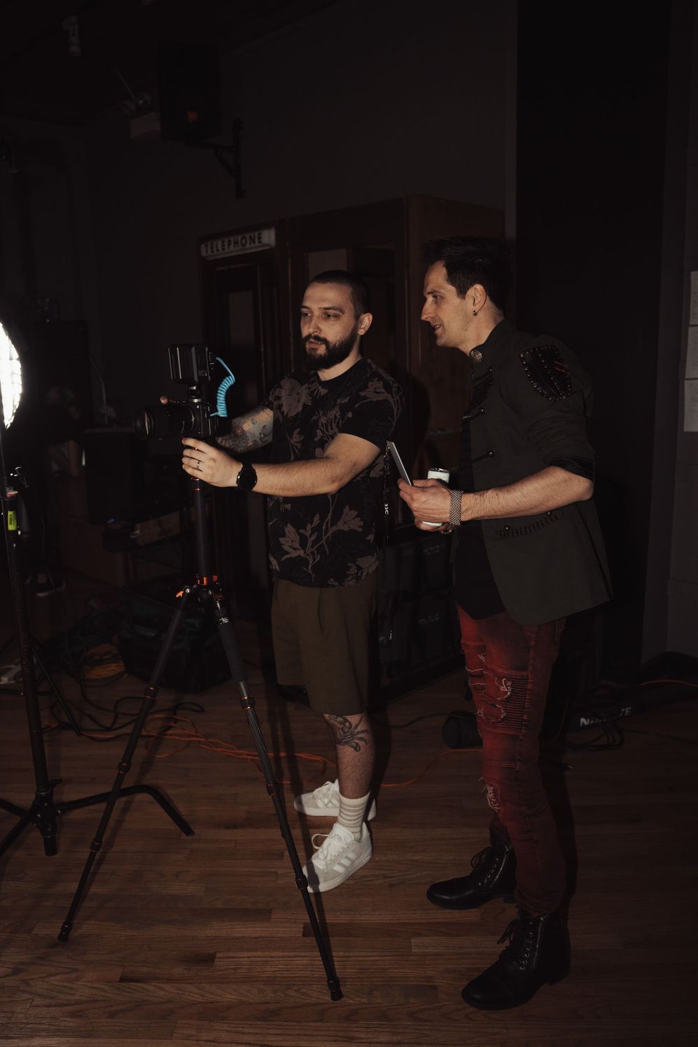 Musicians adjusting equipment during a studio session with dramatic lighting.