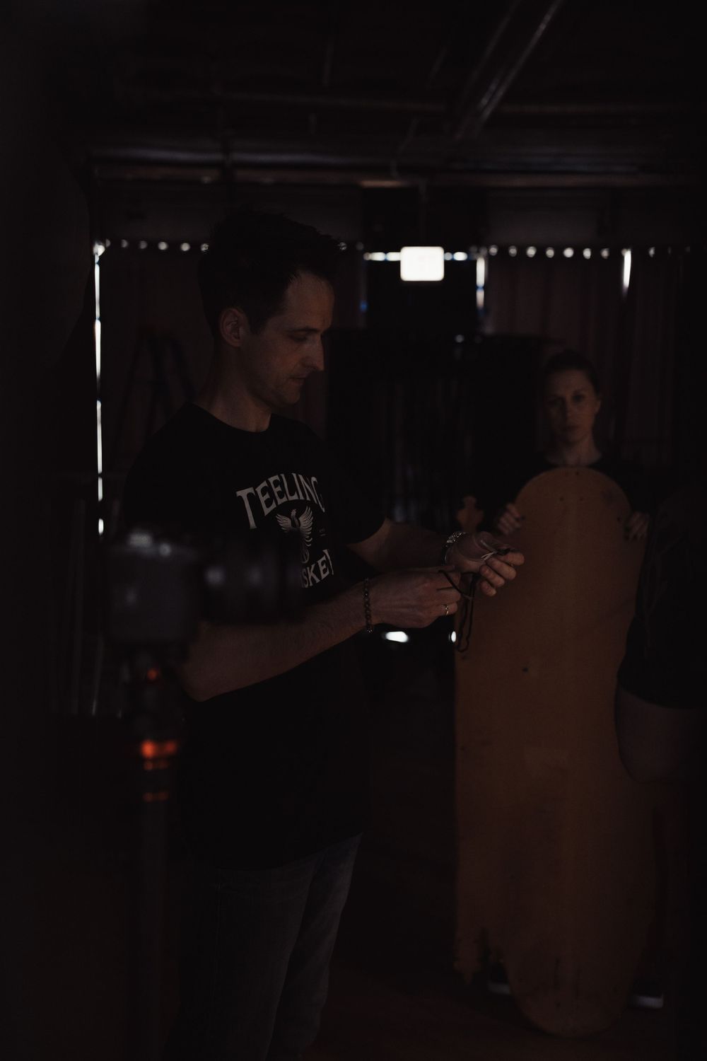 Dark studio setting with person examining equipment in low light conditions.