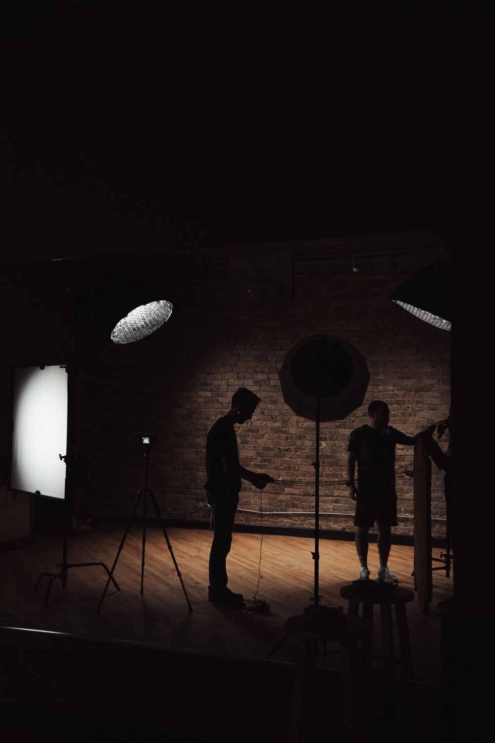 Silhouetted figures working with equipment in a dramatically lit studio space.