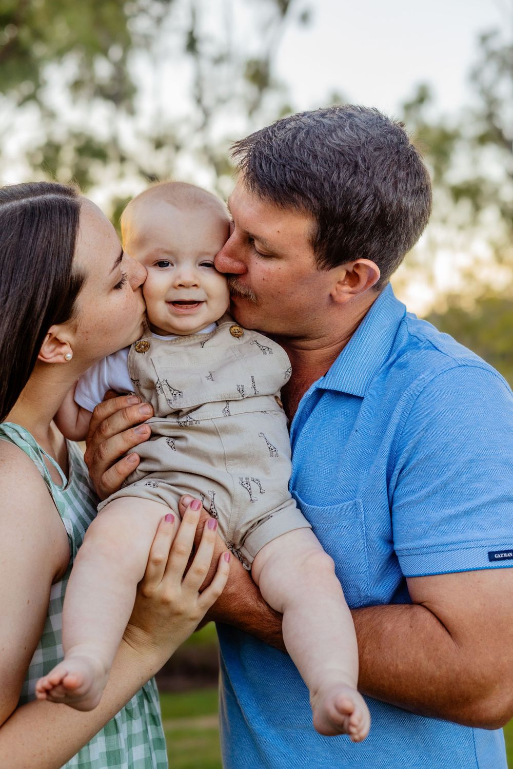 A sweet family moment captured outdoors with everyone sharing kisses and smiles.
