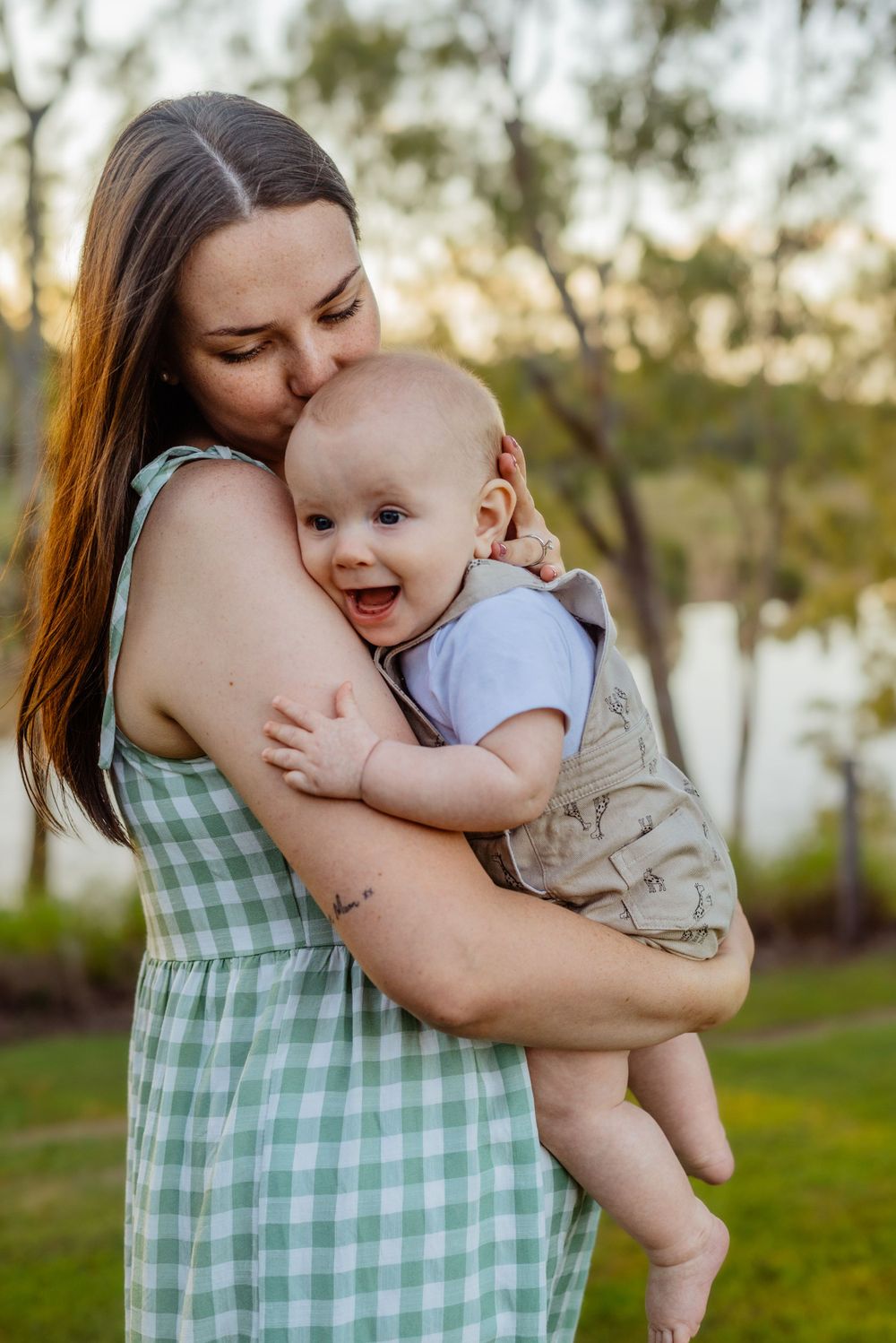 Tender moments between parent and baby wearing light colored clothing in a garden setting.