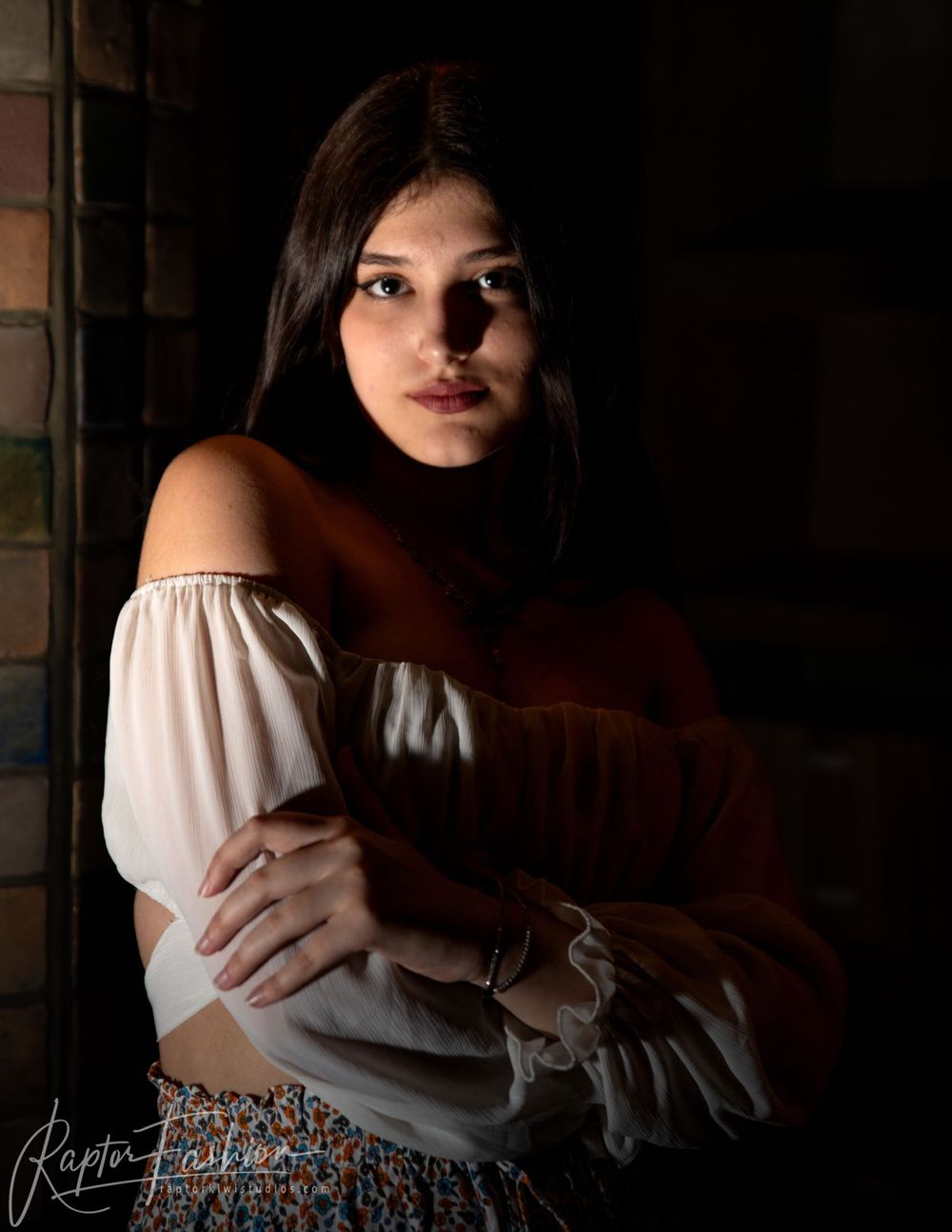 Renaissance inspired portrait with off-shoulder white blouse in dramatic chiaroscuro lighting.