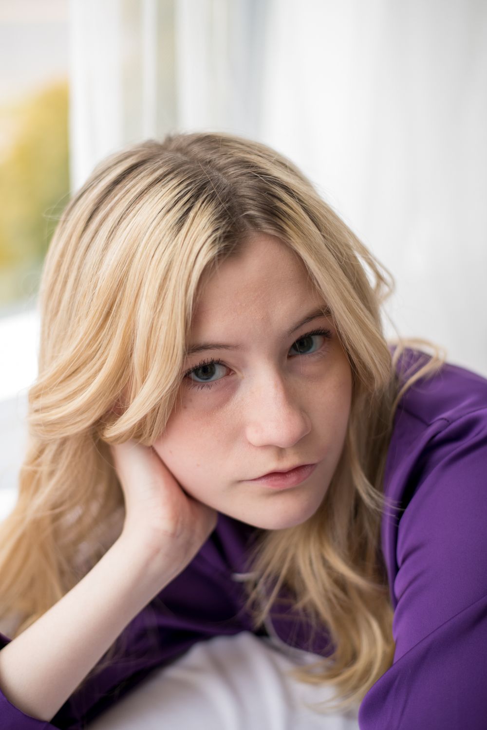 Pensive portrait in purple attire with soft window lighting.