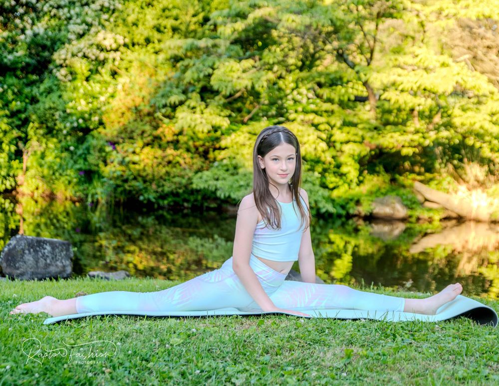 Yoga pose demonstrated on blue mat beside serene pond with lush greenery.