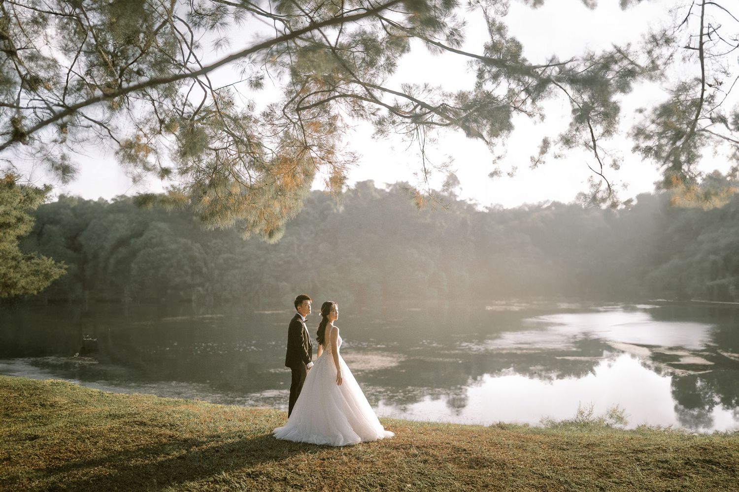 Romantic lakeside wedding portraits during golden hour with natural scenery.