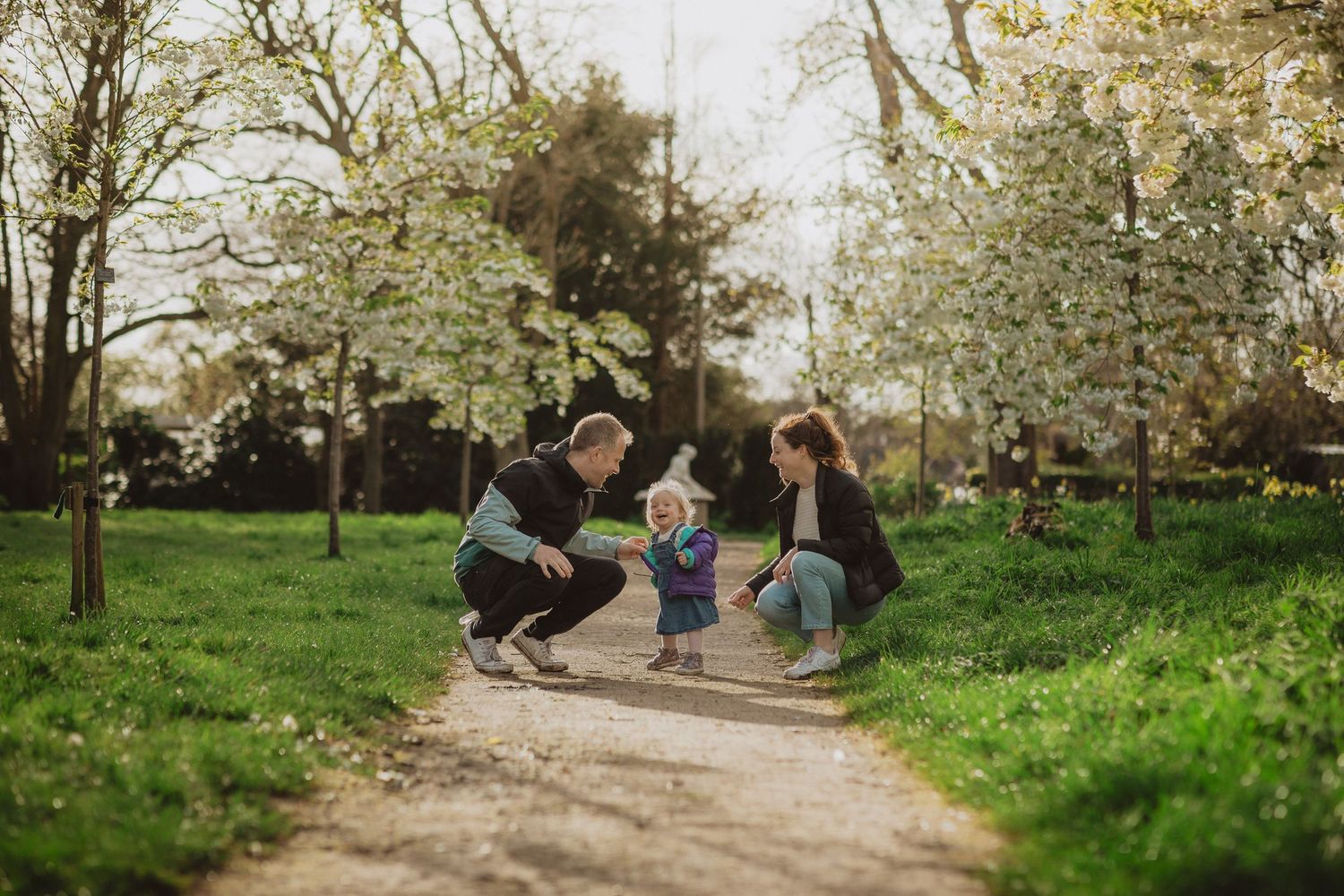 Family enjoying springtime together on a path surrounded by blooming trees.