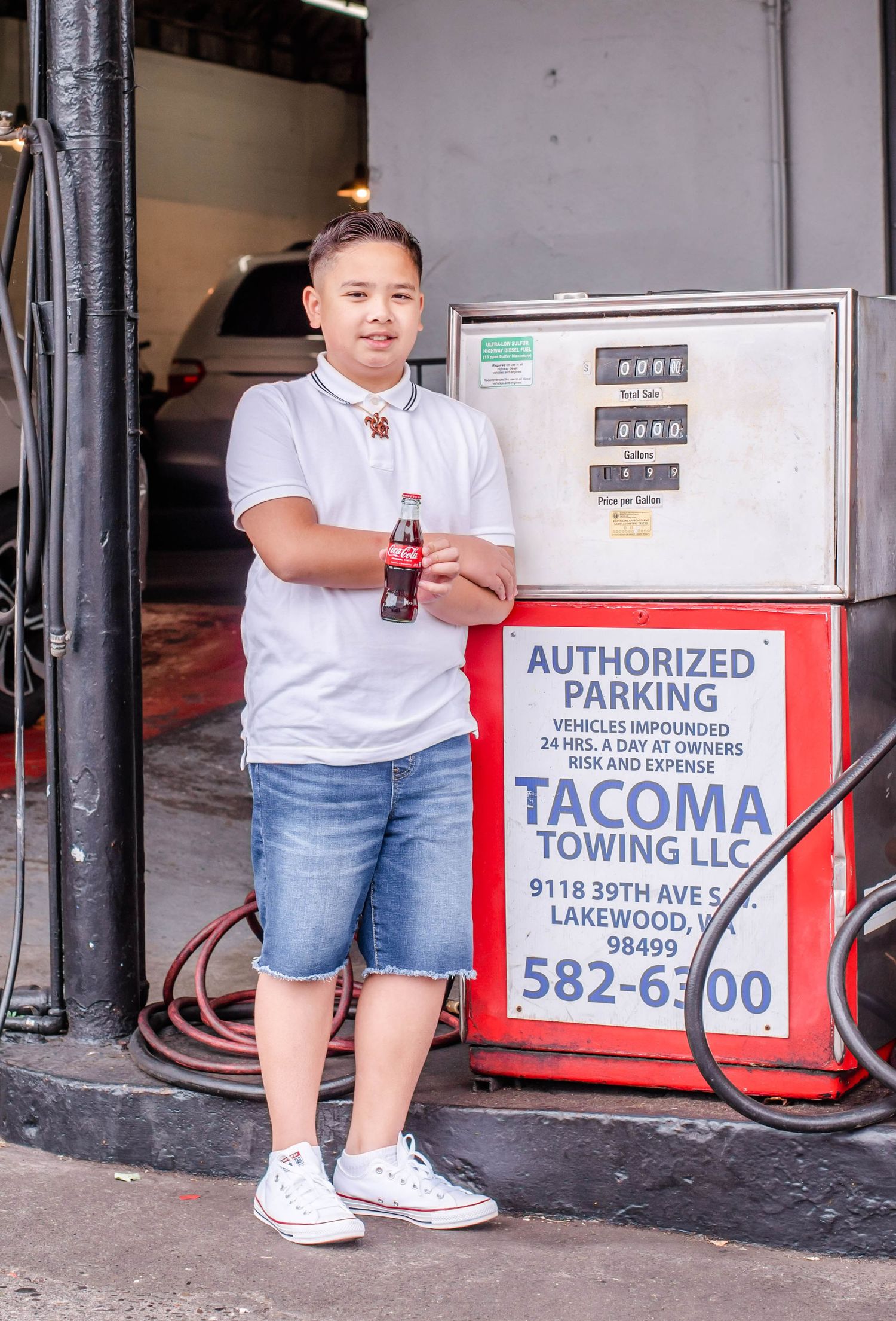 Person seated outside a towing company storefront with red signage.